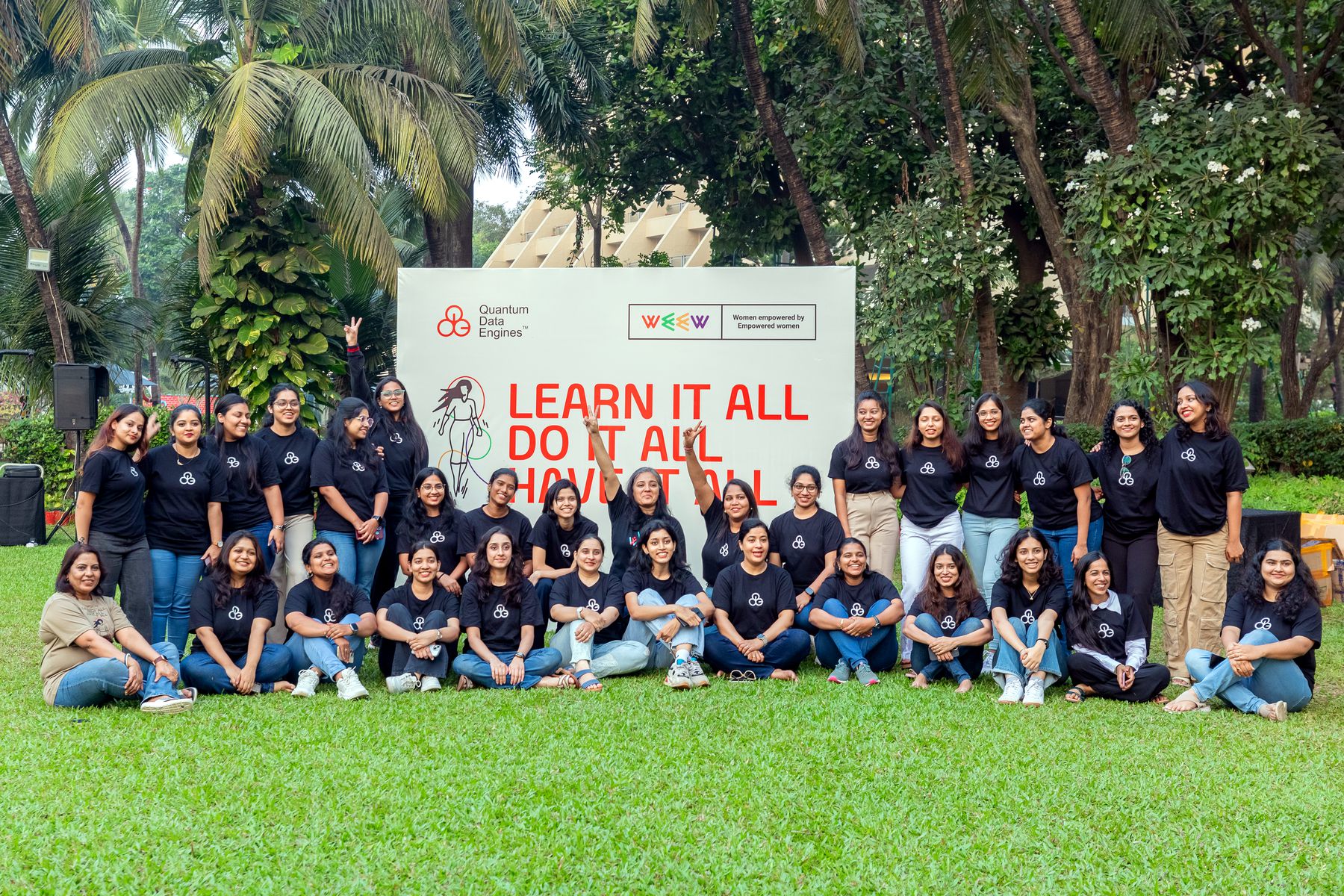 The WEEW cohort together on a lawn in front of the 'Learn it all, do it all, have it all' backdrop