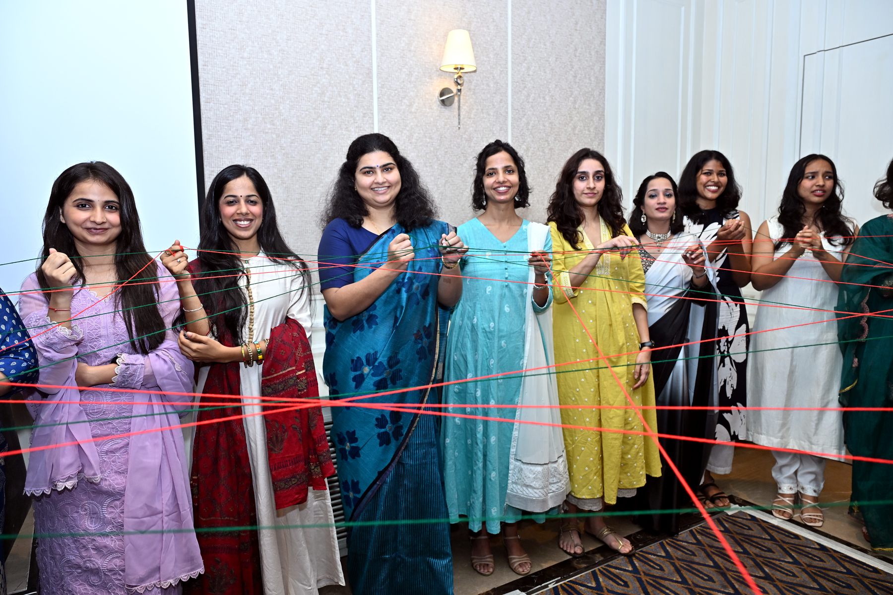 Women holding a web of red thread in a connection exercise